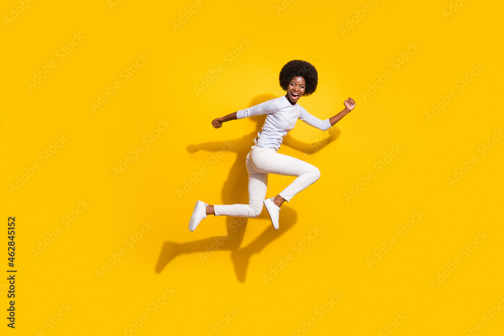 Full length profile side photo of trendy brunette afro american girl jump up run isolated on yellow color background