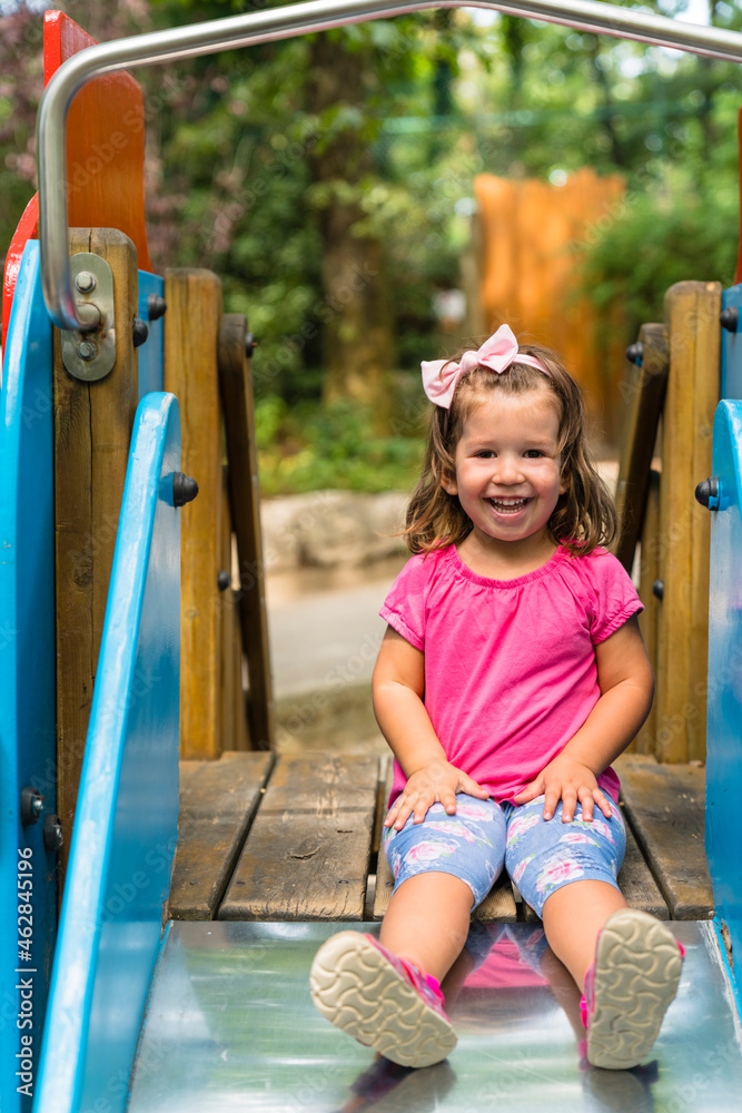 Portrait of happy little girl sitting on playground slide Stock Photo ...