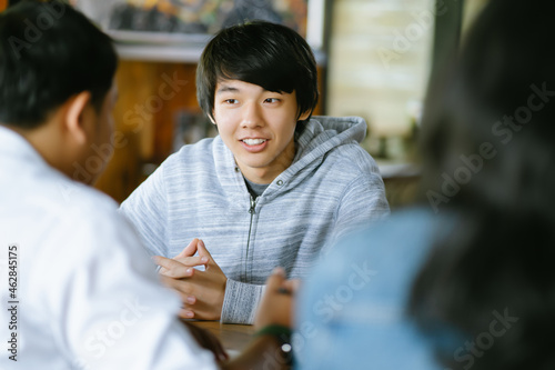 Group of diverse teenagers sitting in the table at classroom and talking. University lecture room with students chatting during break.