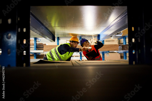 Two workers with torch searching something in factory warehouse photo