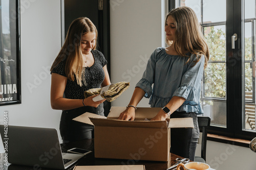 Girls packing scarf in box on table while standing at home