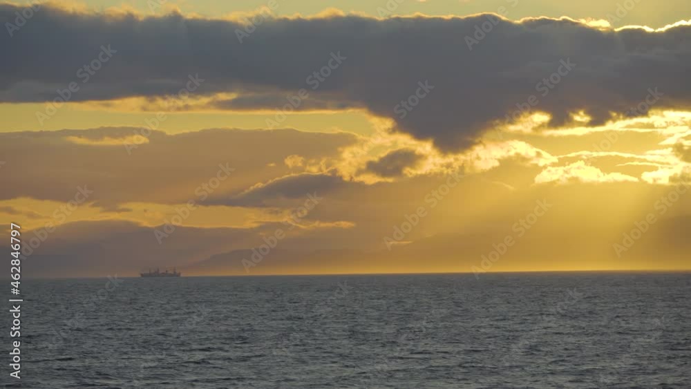 Coast of the Kamchatka Peninsula in Russia. View of the Kamchatka mountains from the sea at sunset. A fishing vessel is sailing along the sea during sunset. Coast of the Kamchatka Peninsula in Russia. View of the Kamchatka mountains from the sea at sunset. A fishing vessel is sailing along the sea during sunset.