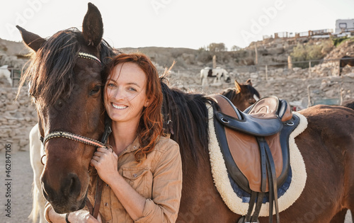 Young farmer woman playing with her horse at farm ranch - Focus on female face photo