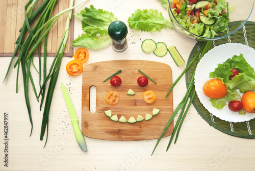 A human face laid out of vegetables on a cutting board. Children's preparation of Italian salad. Flat lay.