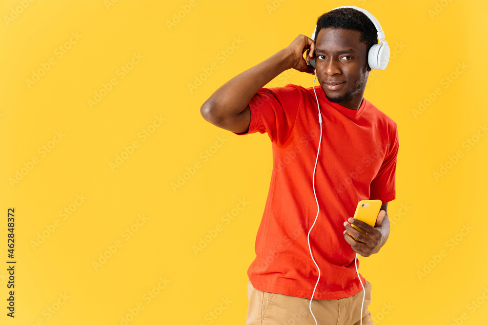 man of african appearance in headphones with a phone listens to music yellow background man of african appearance in headphones with a phone listens to music yellow background