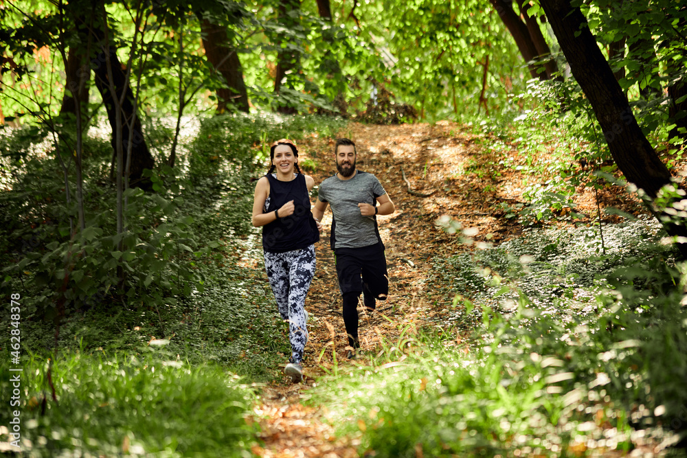 Sporty couple running on forest path Sporty couple running on forest path