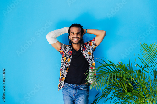 Smiling man with fractured arm posing against blue background