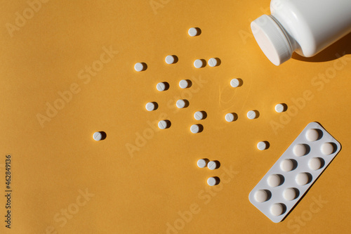 Scattered white pills against a yellow background