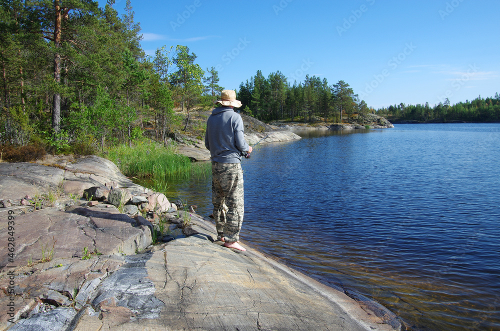 Karelia, Russia - Jule, 2021: A fisherman catches fish on the shores of Lake Ladoga