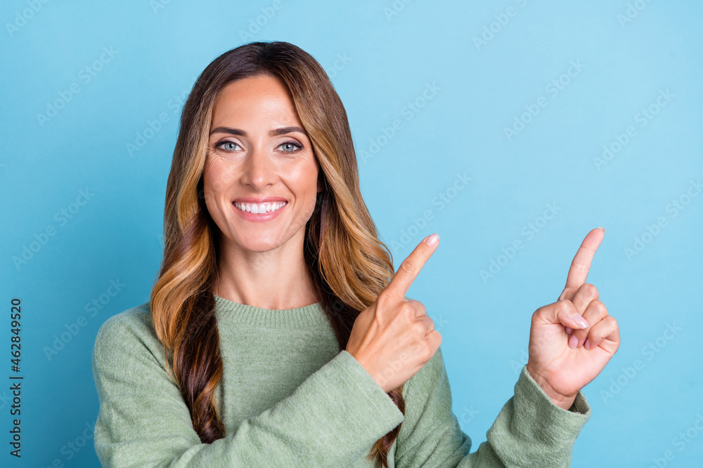 Photo portrait woman wearing green sweater smiling dreamy pointing finger copyspace isolated pastel blue color background Photo portrait woman wearing green sweater smiling dreamy pointing finger copyspace isolated pastel blue color background