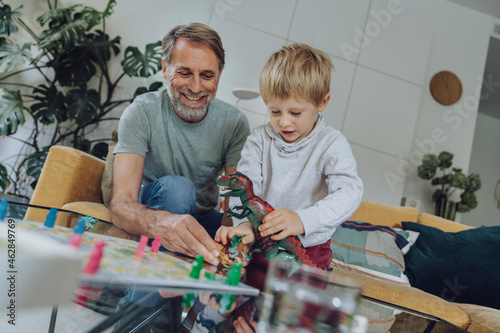 Father playing with son while sitting on sofa in living room photo