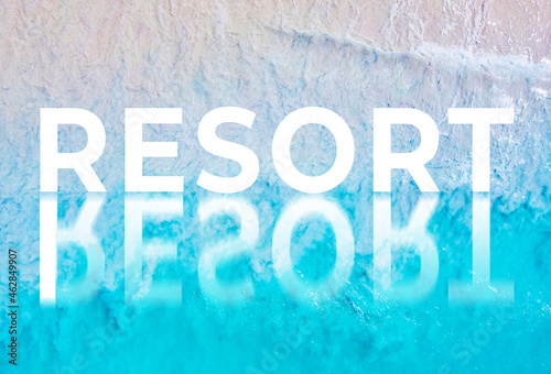 The word RESORT written by the ocean with a wave on the beach. Background for advertising
