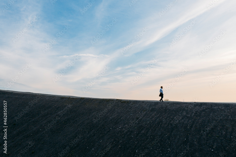Male entrepreneur walking on hill against sky during sunset Male entrepreneur walking on hill against sky during sunset