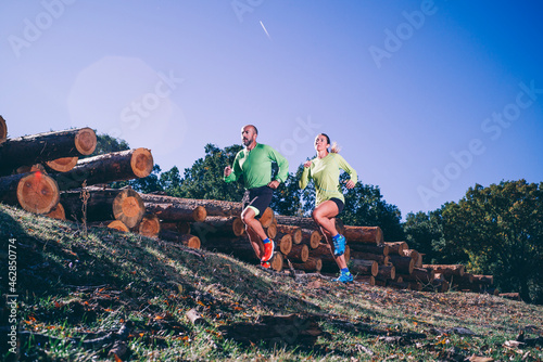 Mature couple running on land against clear blue sky in forest photo