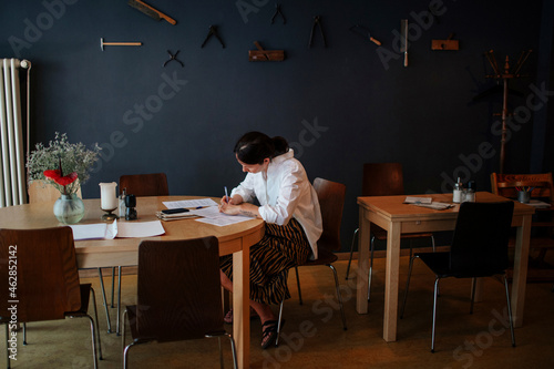 Female owner analyzing financial bills on table while sitting in coffee shop photo