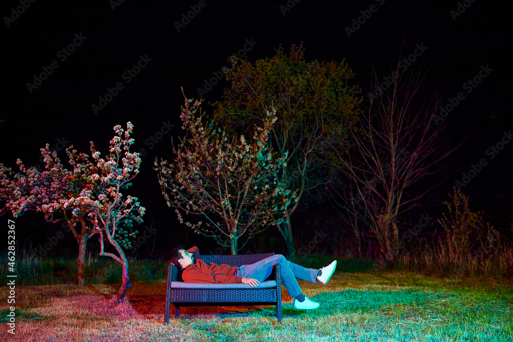 Sad man sitting alone on garden bench at night Stock Photo | Adobe Stock