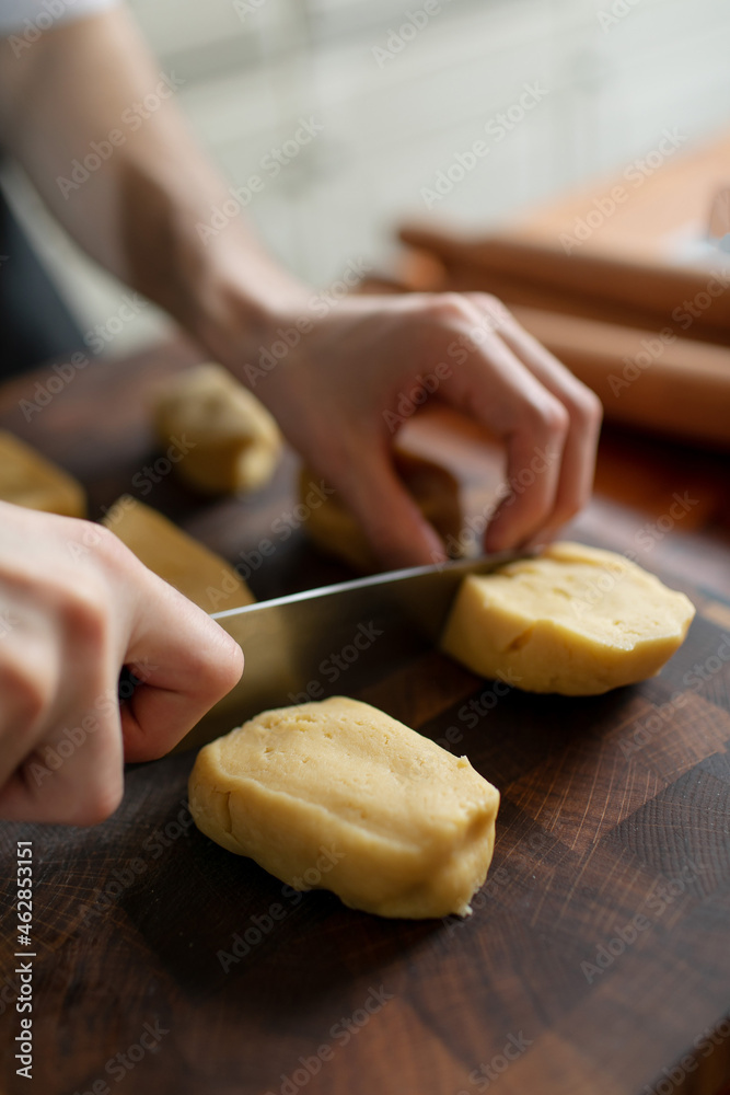 Yeast dough divided into pieces. Chef's hands with a knife. Technique for making sweet pastries at home