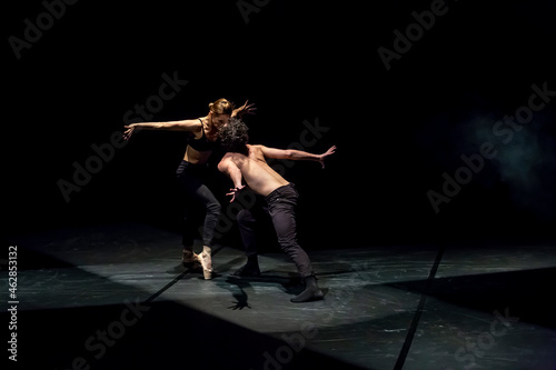 Male and femal dancer performing contemporary ballet on black stage photo