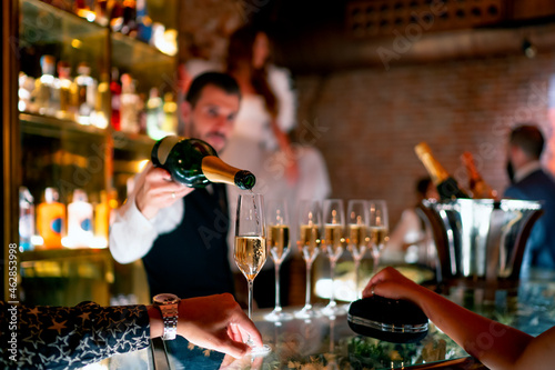 Bartender serving drink to man and woman at bar counter in pub photo