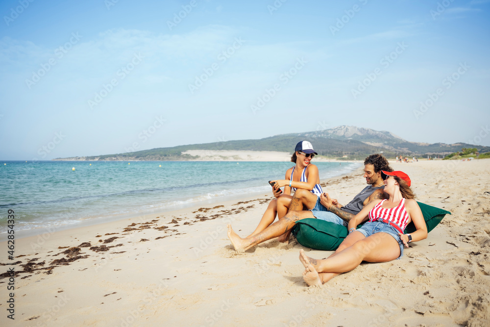 Male and female friends relaxing at beach during vacation, Tarifa, Spain Male and female friends relaxing at beach during vacation, Tarifa, Spain