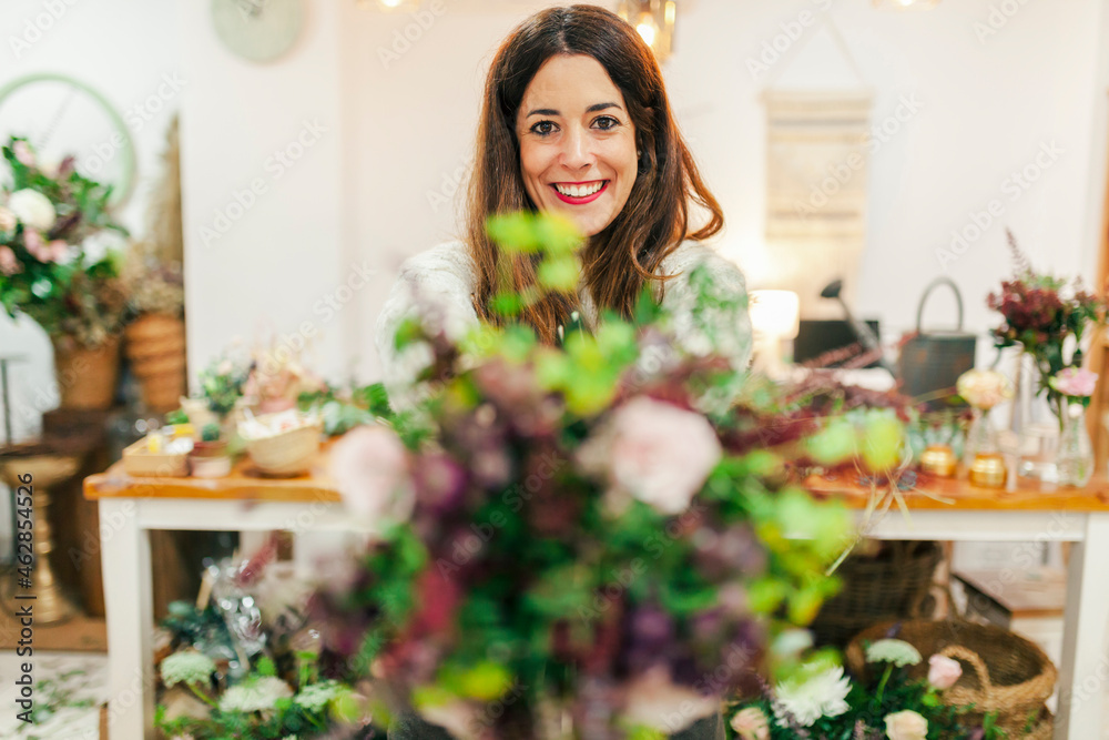 Smiling woman holding bouquet while standing at flower shop Smiling woman holding bouquet while standing at flower shop