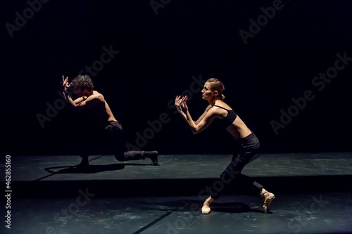 Male and femal dancer performing contemporary ballet on black stage