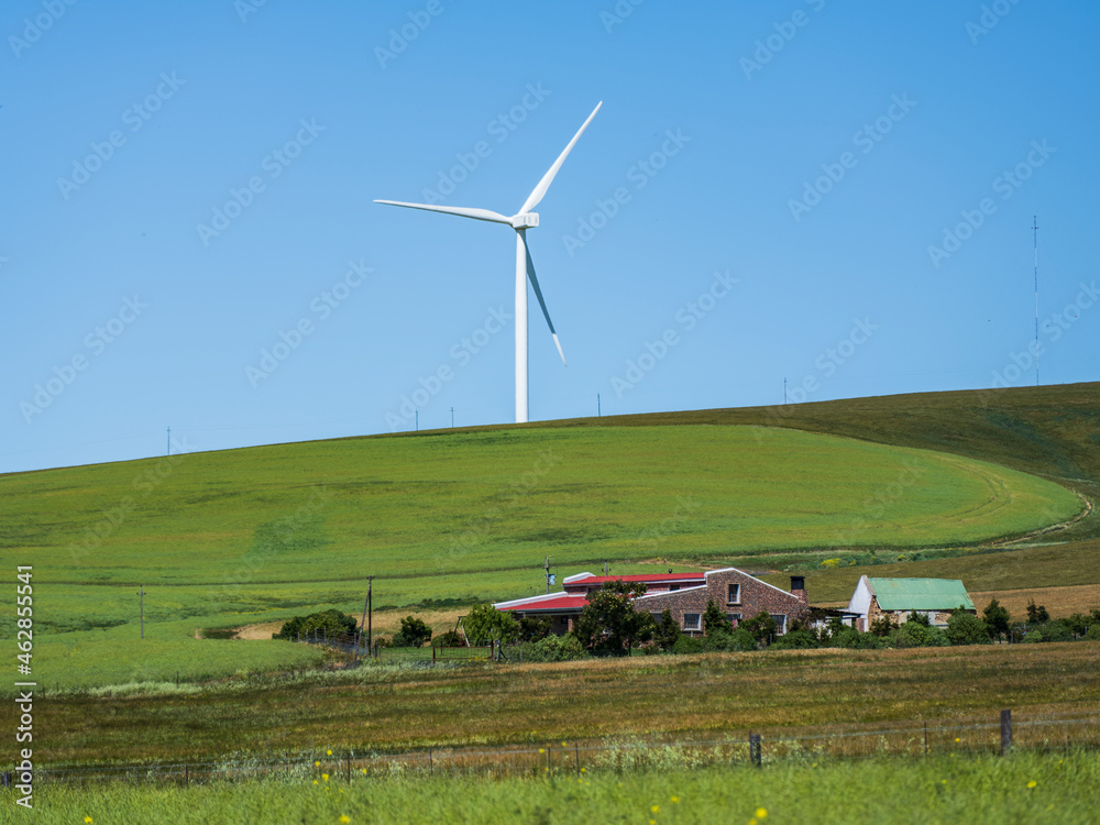 Fototapeta premium Close up shot of countryside house and a wind turbines with blue sky in the overberg Western Cape South Africa
