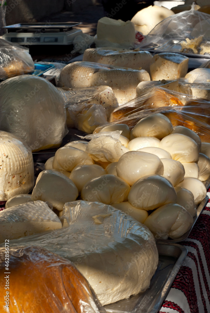 Obraz premium Different types of cheese on the table. Many cheese is sold at an agricultural fair. Natural home product. Contrasting dramatic light as an artistic effect.