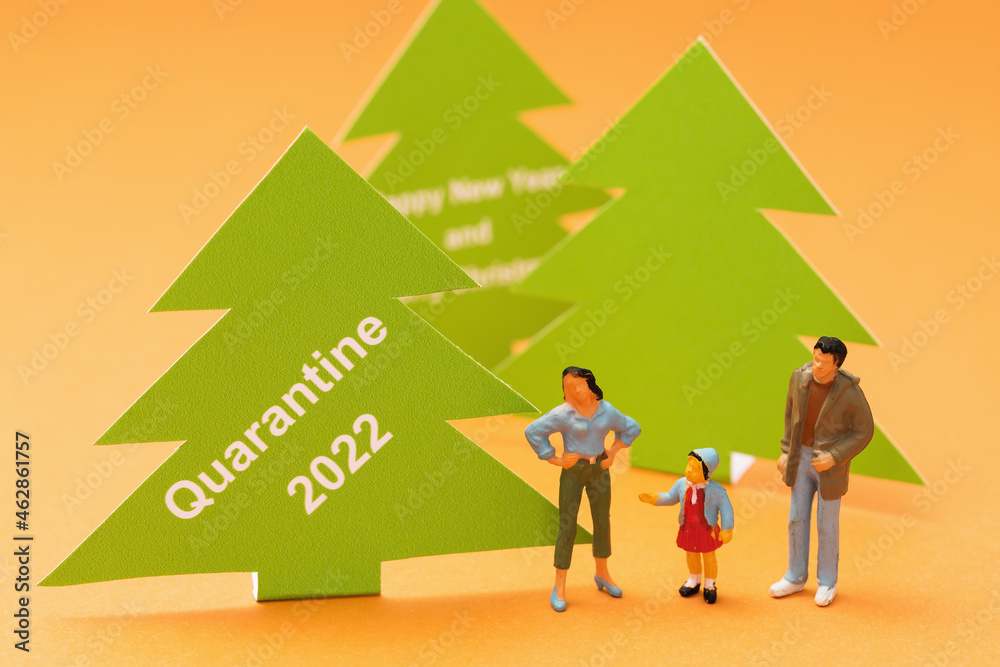 Fototapeta premium Toy men made of plastic and Christmas trees made of paper with text on a colored background, a concept on the topic of quarantine for the new year