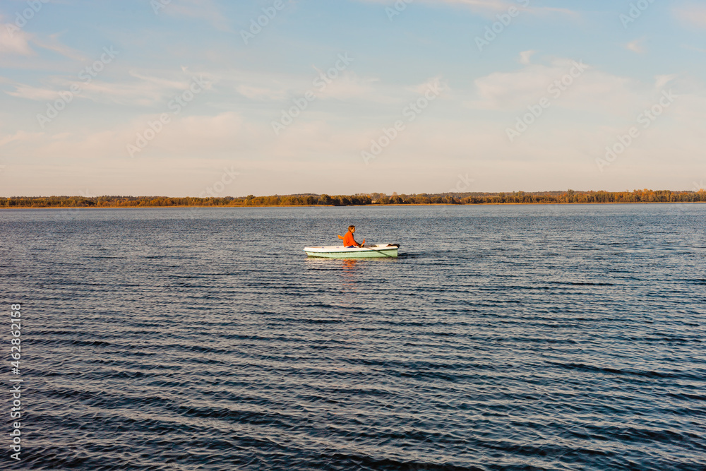 rybak w łódce na jeziorze o świcie, wschód słońca nad jeziorem rybakiem w łódce
