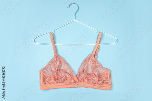 Top view of stylish women bra on white hanger on light blue background with copy space. Women's wardrobe