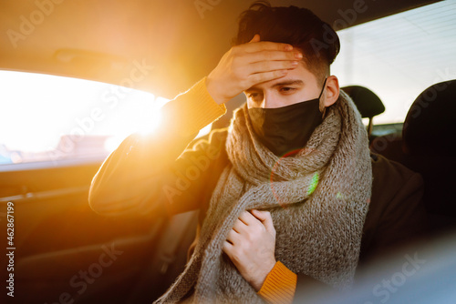 Young man in protective sterile mask on a back seat coughing. Covid-2019. Healthcare, virus, allergy concept.