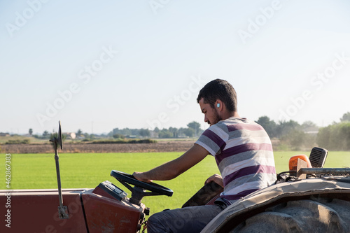 young farmer plowing with a tractor while listening to music