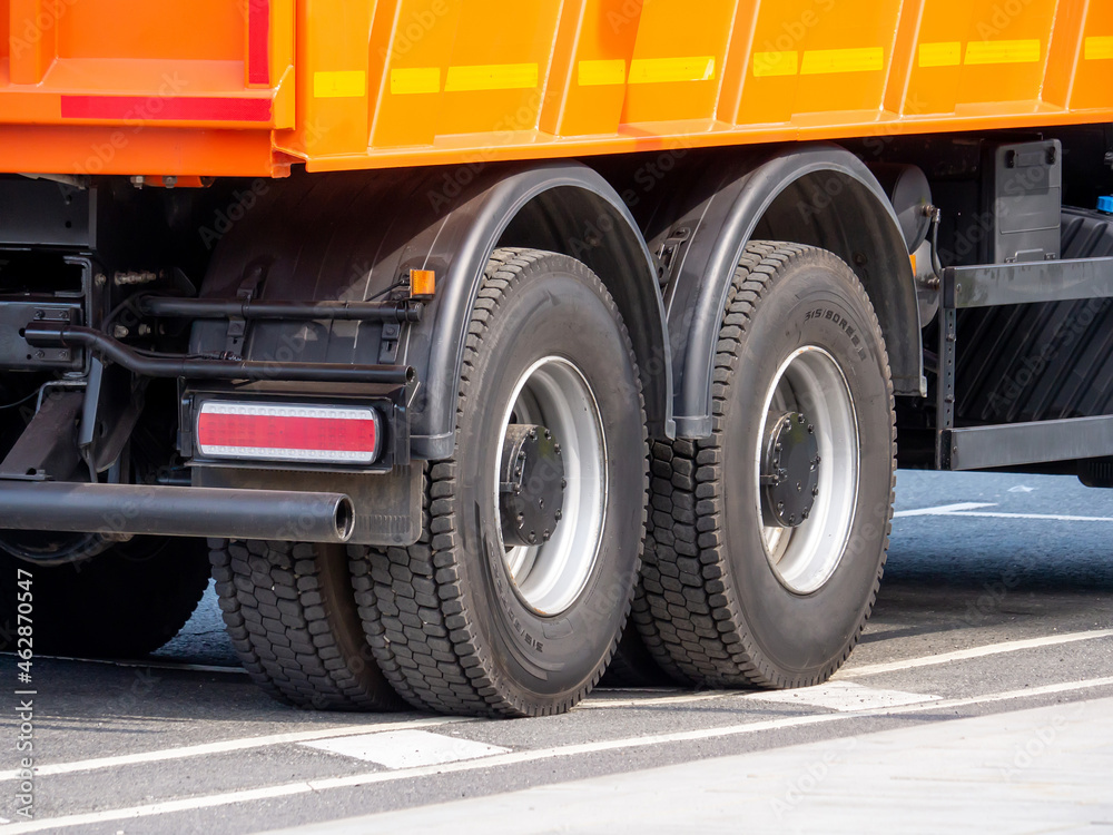 Dump truck wheels with allseason tires on an asphalt road. A closeup