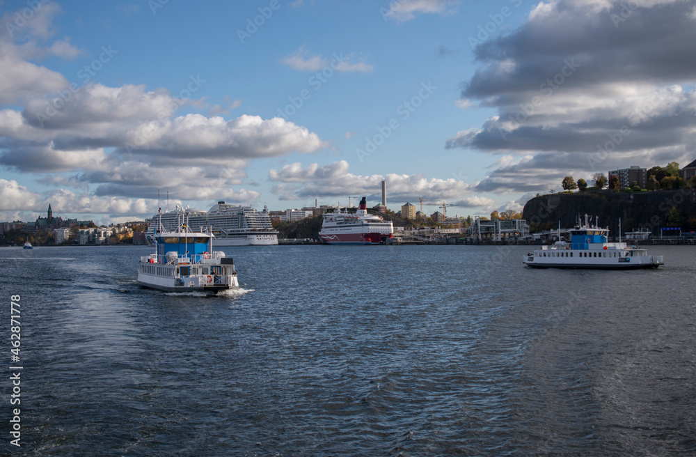 Commuting boat arriving to the pier at old town Gamla Stan with commuting boat and ferries in the background a color full autumn day in Stockholm
