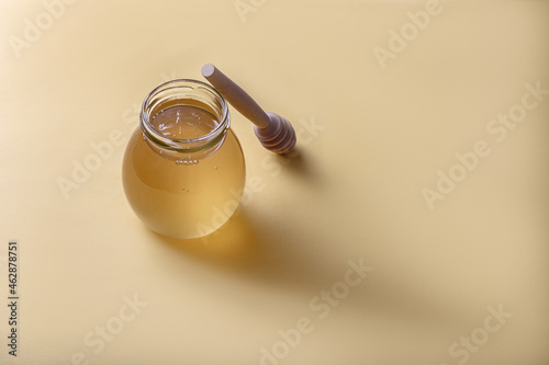 Honey background. Sweet honey in a glass jar and honey spoon.