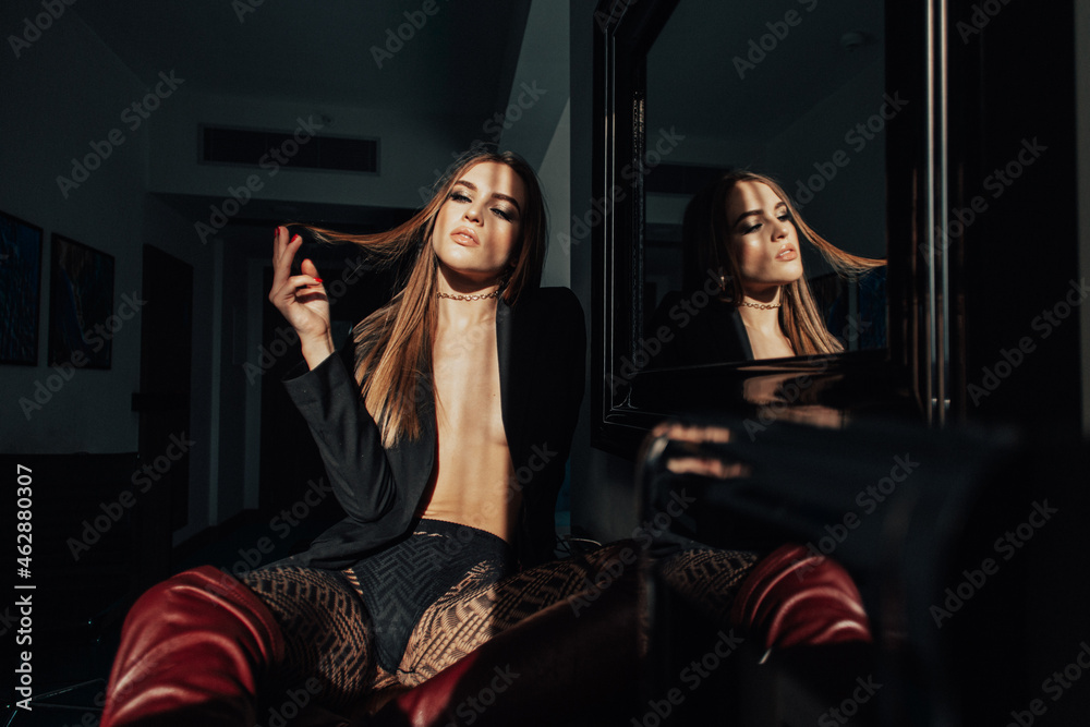 sunny morning, the room is very beautiful, a young girl, she is wearing a black jacket on a naked body and high boots, the sunlight from the window brightly illuminates her