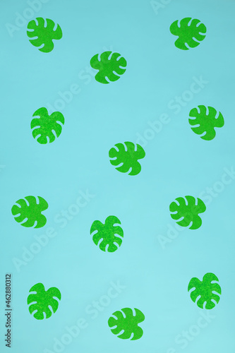 Tropical  summer concept. Exotic green leaves on turquoise background. Wild nature and sea color idea. Minimal flat lay pattern.