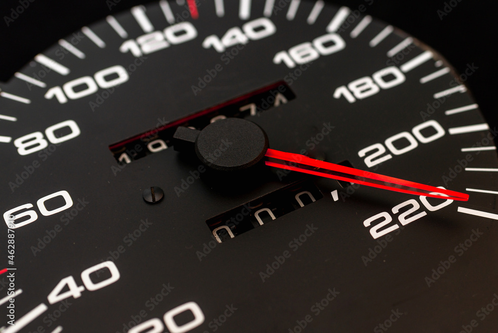 Car speedometer. Auto car speedometer shows 220 km h or miles.Closeup shot,dark black background.Automobile dangerous speed concept Car speedometer. Auto car speedometer shows 220 km h or miles.Closeup shot,dark black background.Automobile dangerous speed concept
