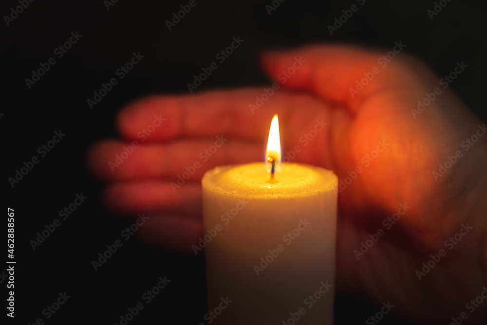 One palm take care of candle fire at night.Selective focus,Dark black background.Closeup. One palm take care of candle fire at night.Selective focus,Dark black background.Closeup.