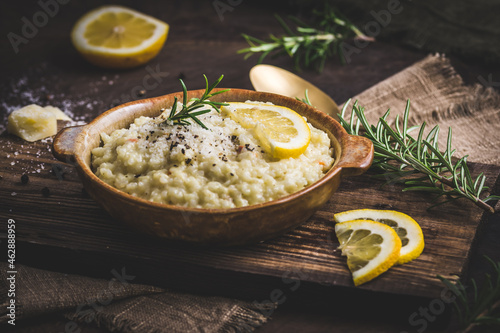 Lemon rice risotto with rosemary on dark wooden background