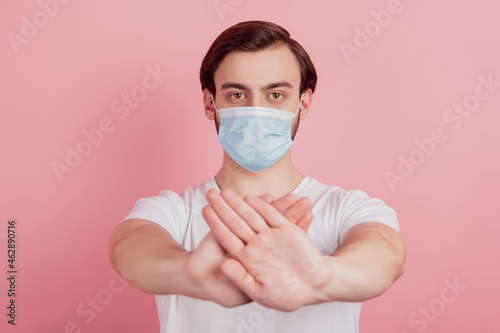 Portrait of protester guy wear medical respirator raise hand show stop covid sign on pink background