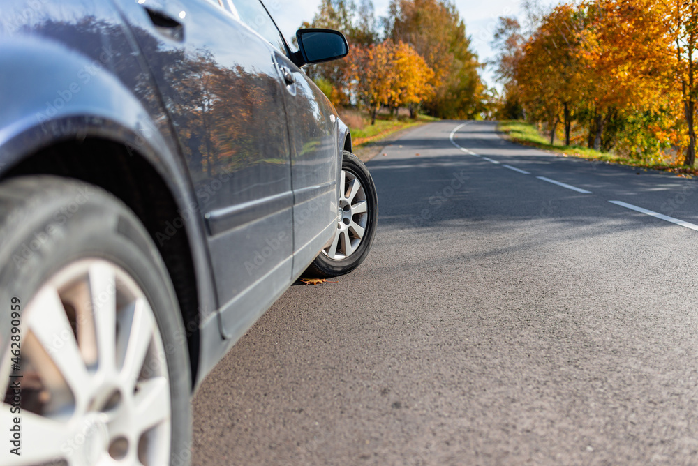 Car on asphalt road on autumn day at forest or park.Selective focus,copy space.