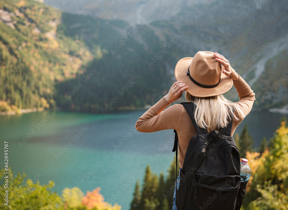 Woman traveler wearing hat and looking at amazing mountains and lake