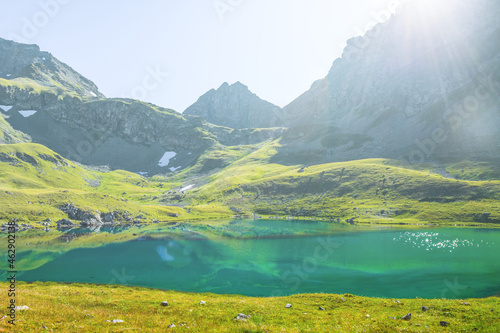 blue calm lake in mountain valley under sparkle sun, mountain travel background