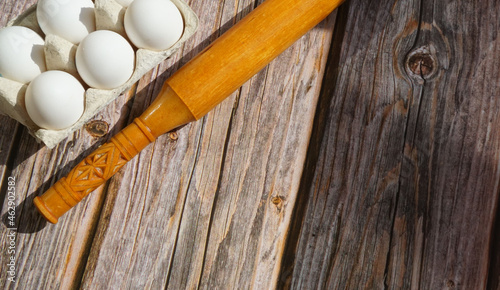 white chicken eggs wooden rolling pin on wooden surface sun rays breakfast baking ingredients