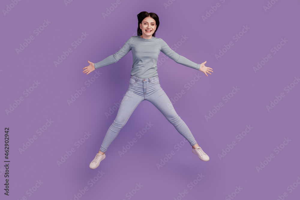 Full length photo of young excited girl have fun jump up active glad isolated over purple color background