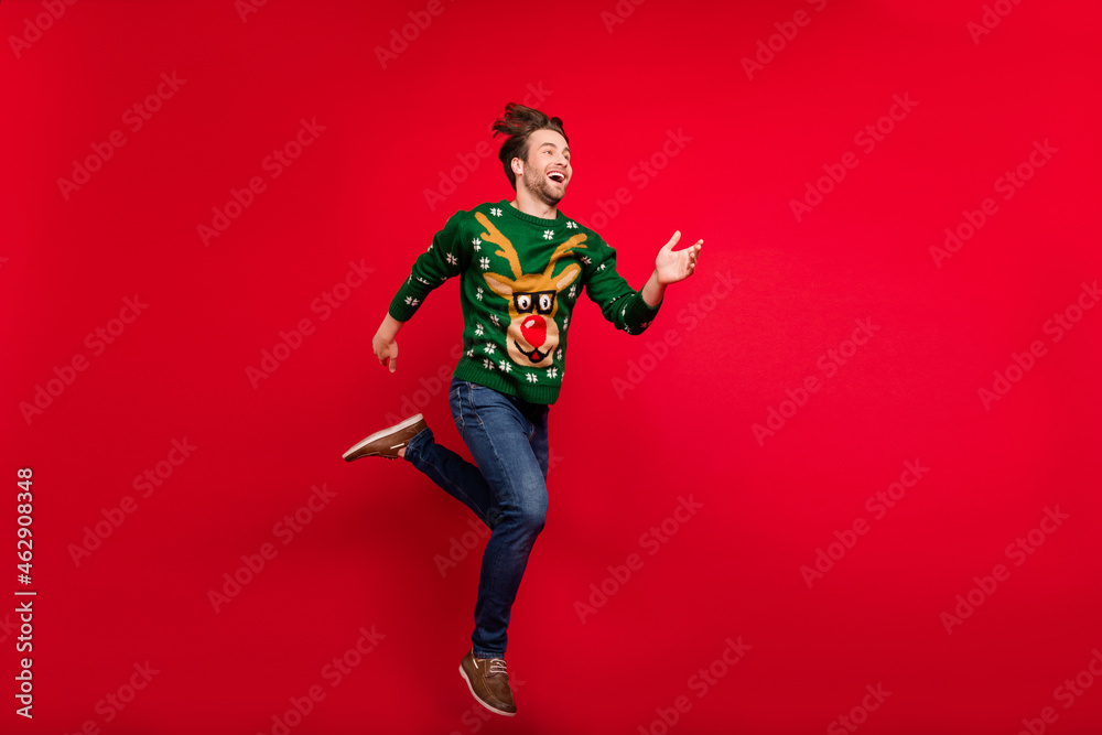 Full size photo of smiling good mood guy running fast speed in air wear ugly sweater isolated on red color background