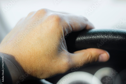 Close up shot of a man's hands holding a car's steering wheel.