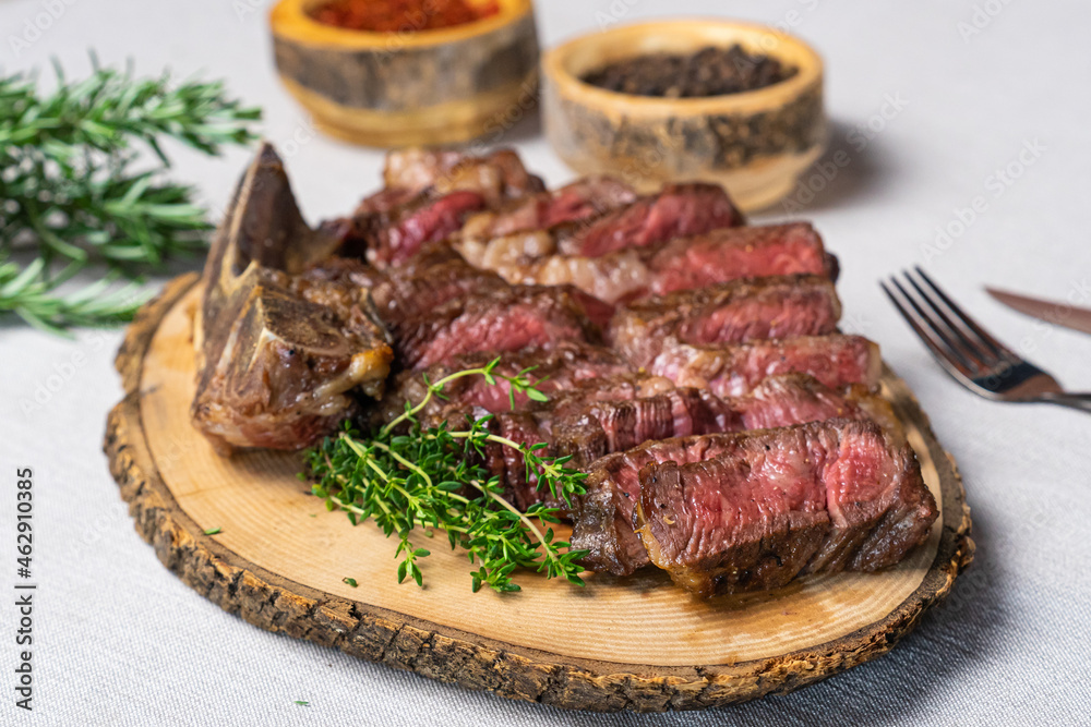 Sliced medium rare grilled beef steak on wooden cutting board with spices Sliced medium rare grilled beef steak on wooden cutting board with spices